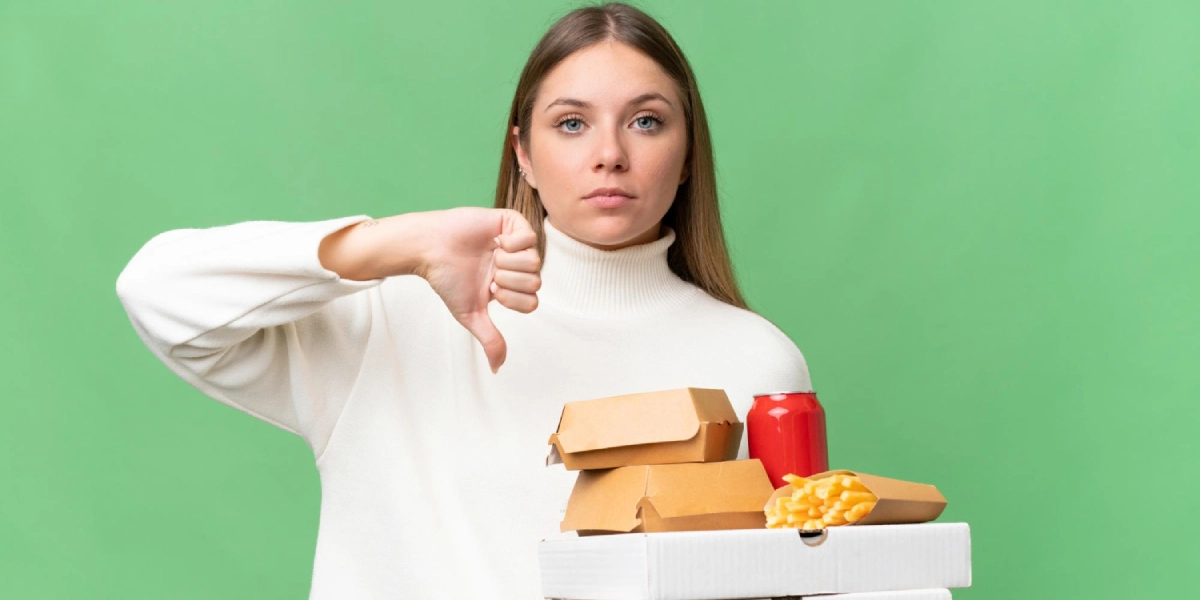 Kobieta trzyma fast food i pokazuje kciuk w dół